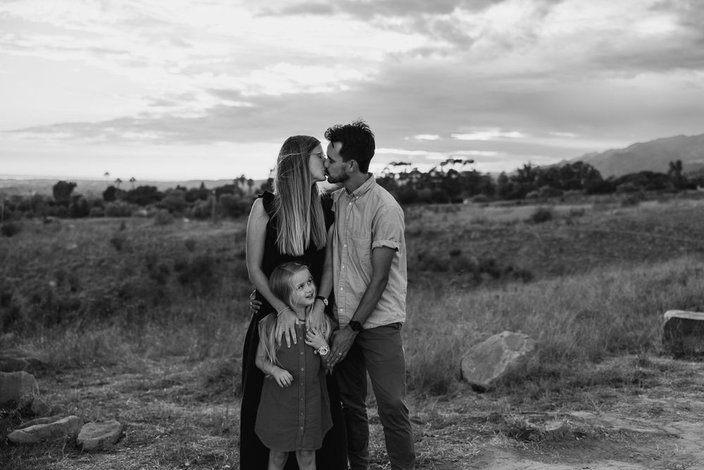 A monochrome family portrait in a rugged desert setting at dusk.