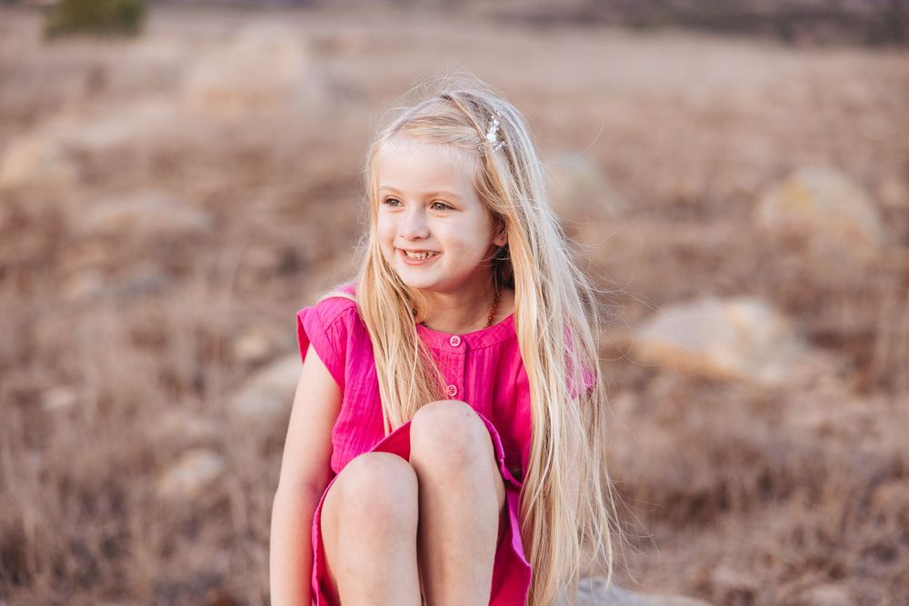 A bright pink dress stands out against a desert landscape on a sunny day.