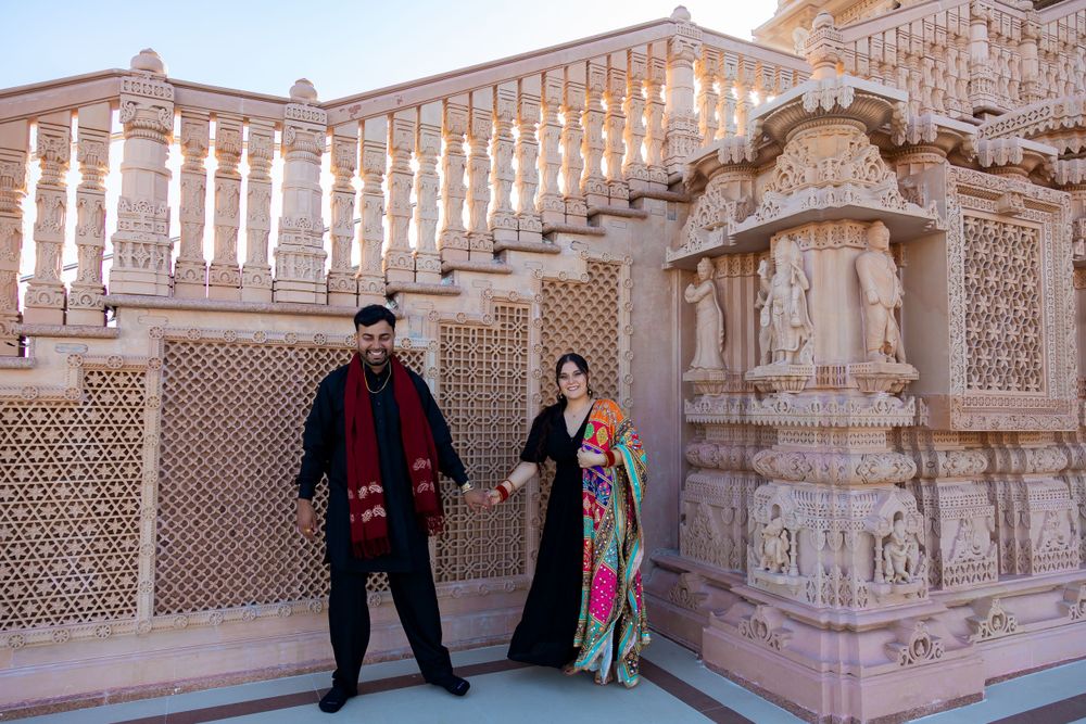 Two people pose against ornate carved marble architecture at a historical Indian monument.