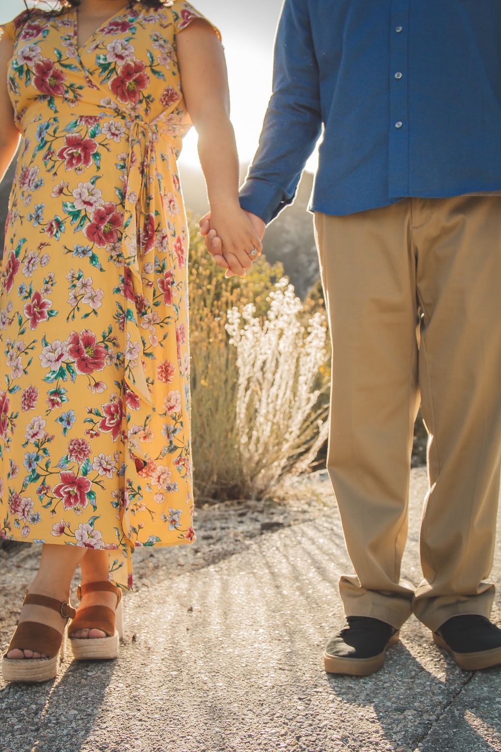 Close-up shot of couple's feet as they hold hands on a path.