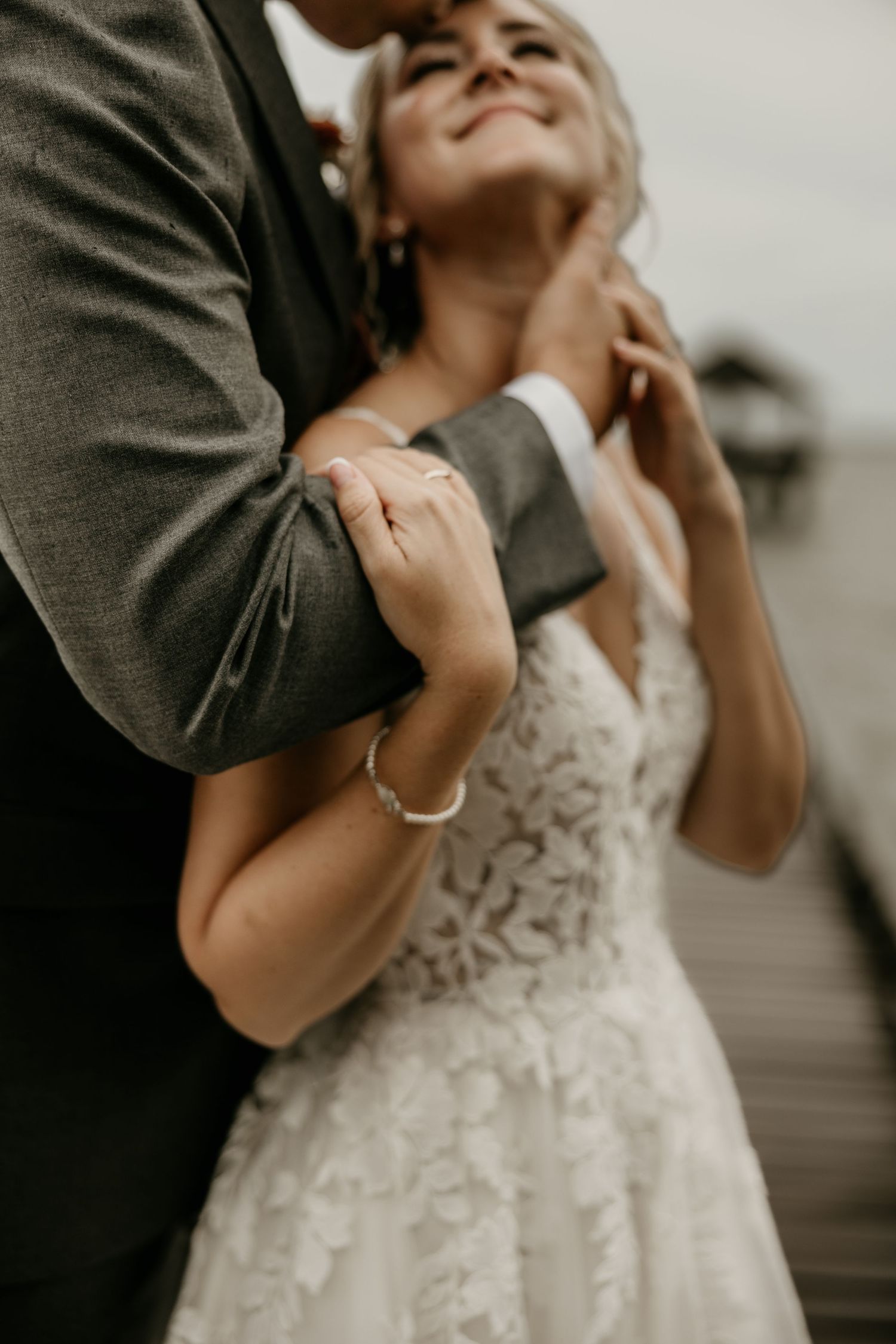 Intimate wedding moment showing lace dress detail and gentle embrace.