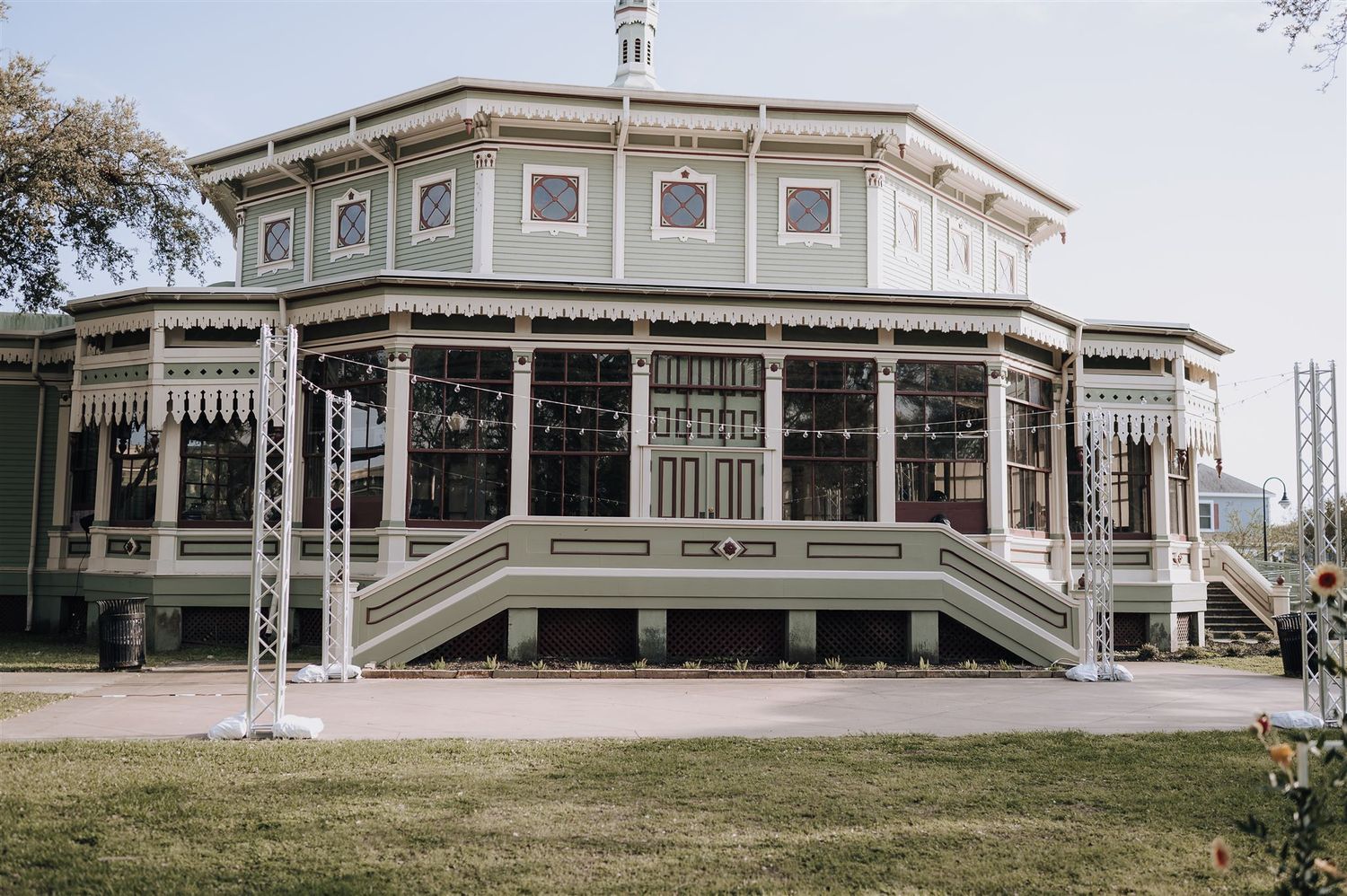 A Victorian-style gazebo with ornate white trim and architectural details stands on a grassy lawn.