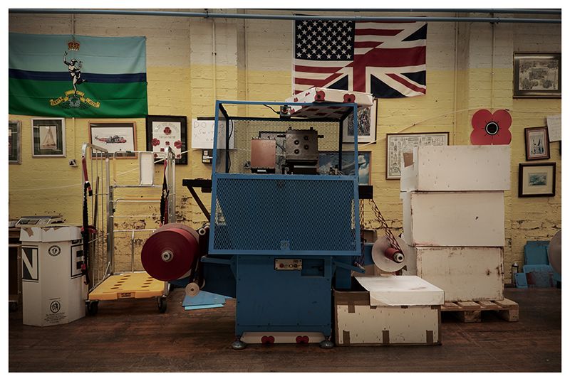 Workshop interior with blue machinery and American and British flags on display.