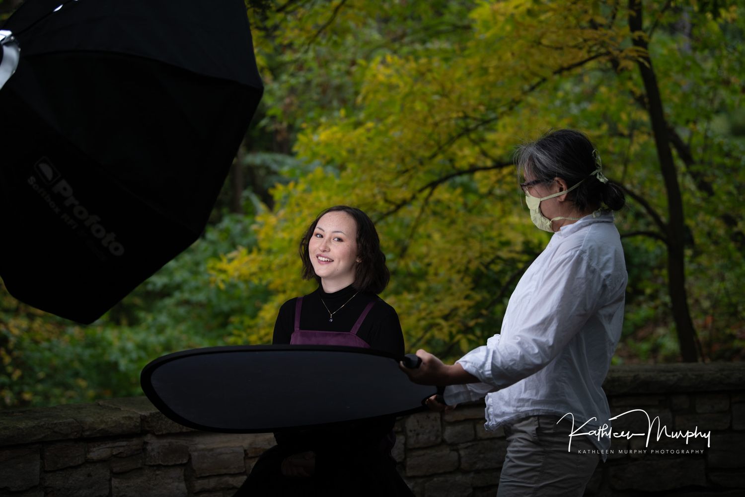 Behind the scenes photo shoot in a park with lighting equipment and reflectors.