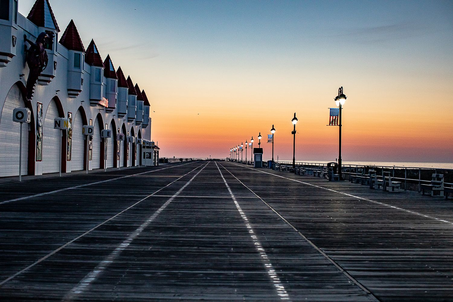 Boardwalk with Victorian buildings and lampposts at sunset.