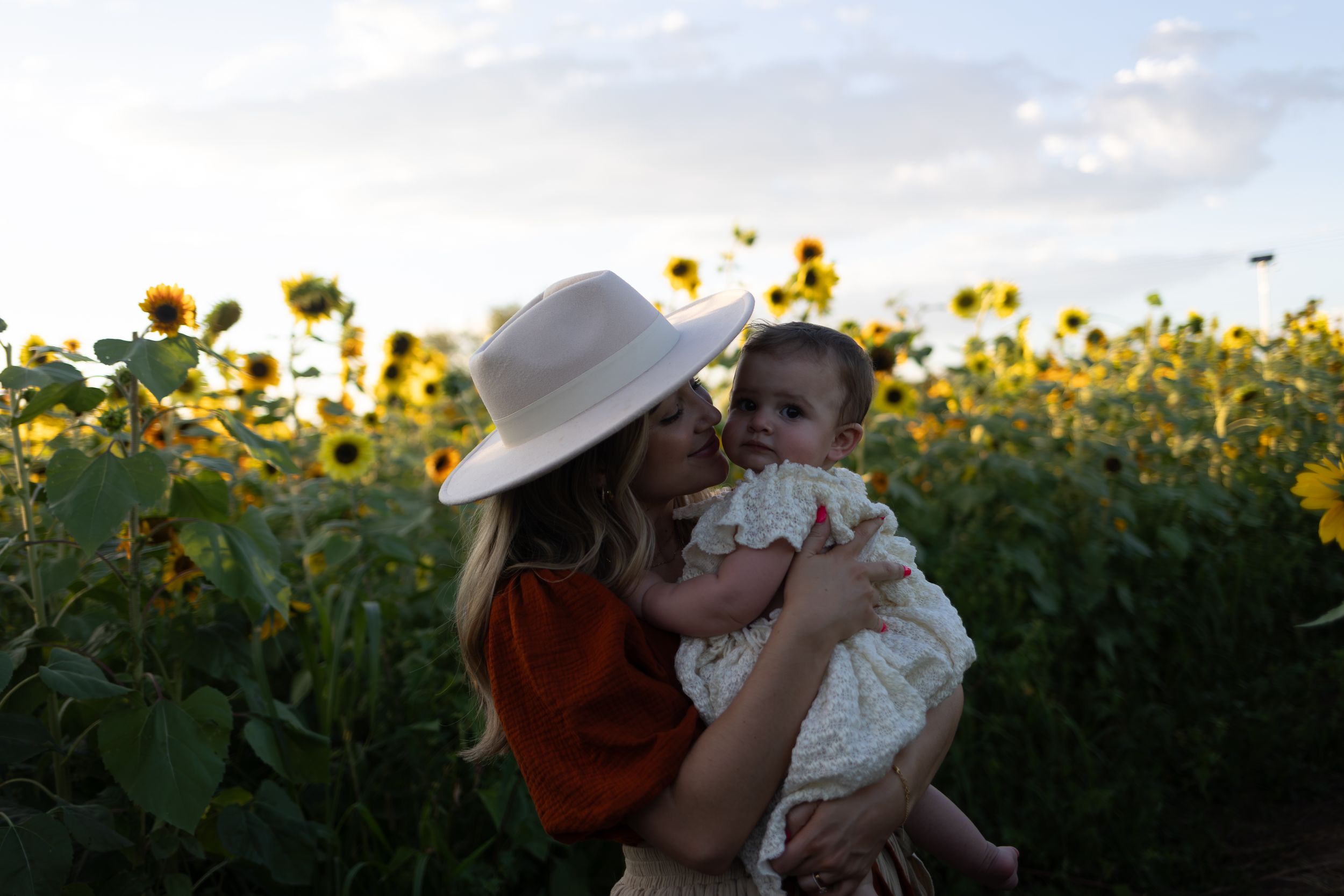 Silhouette portrait in a sunflower field during golden hour.