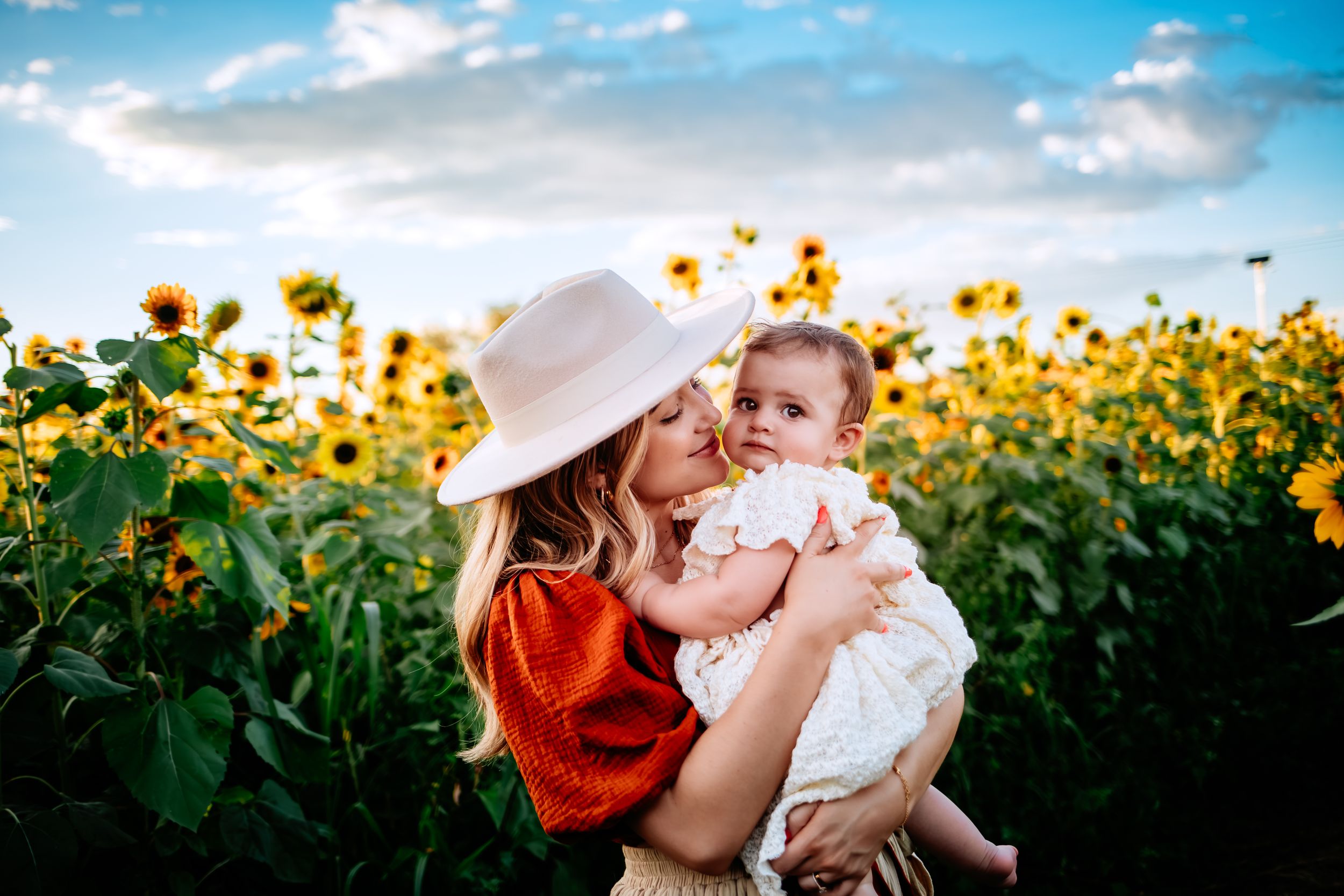 Intimate family portrait among blooming sunflowers under summer skies.
