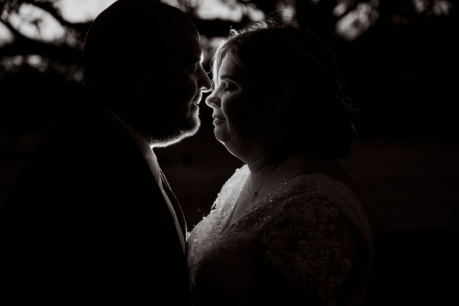 Dramatic backlit portrait captures tender moment between couple in silhouette.