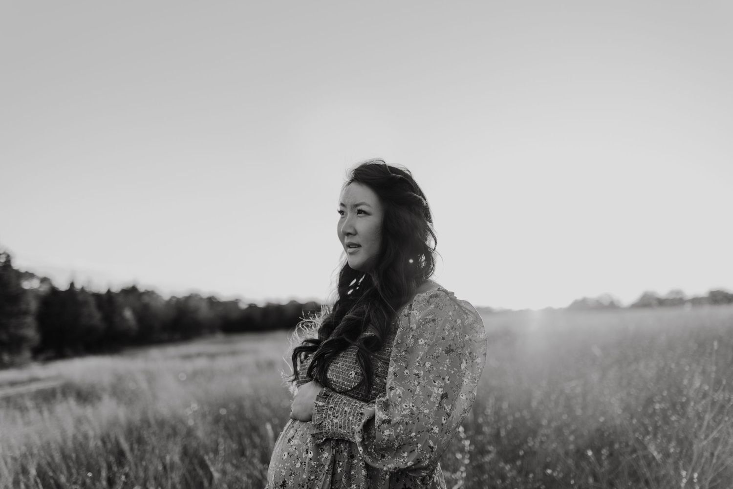 Sun-drenched portrait in black and white of person standing in meadow.