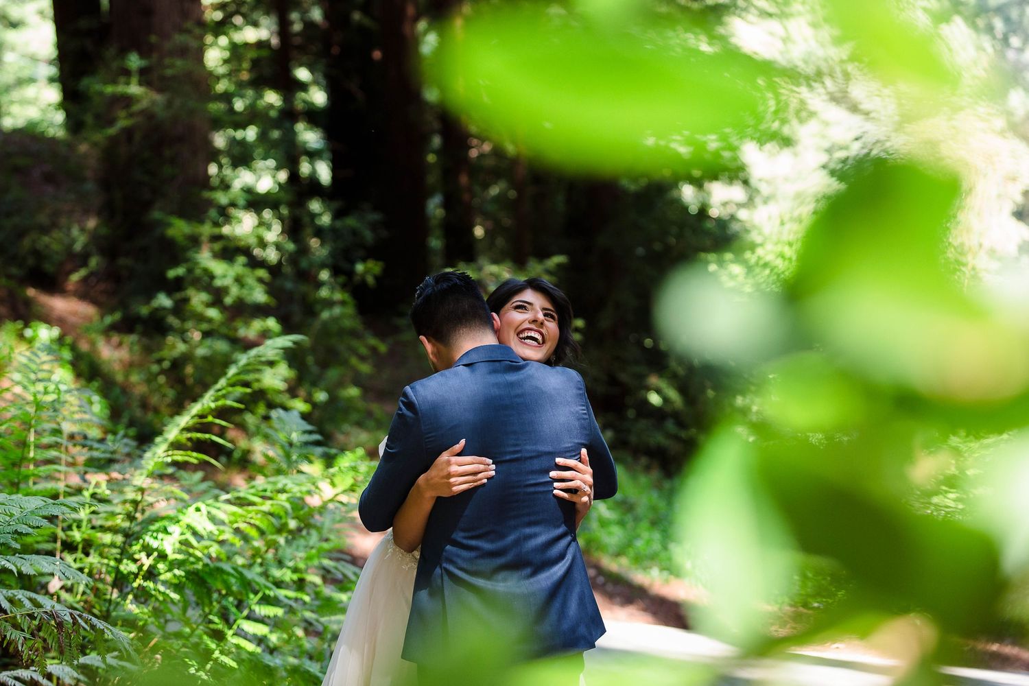 An intimate embrace captured through soft green foliage in a forest setting.