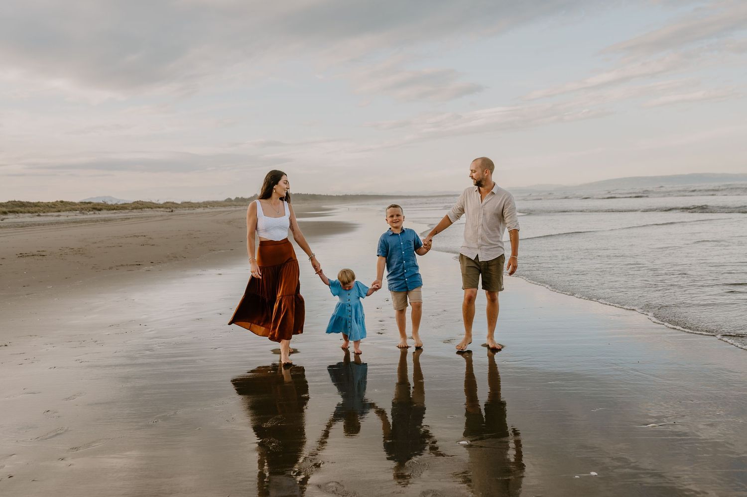 Silhouettes of family walking together along beach at sunset.