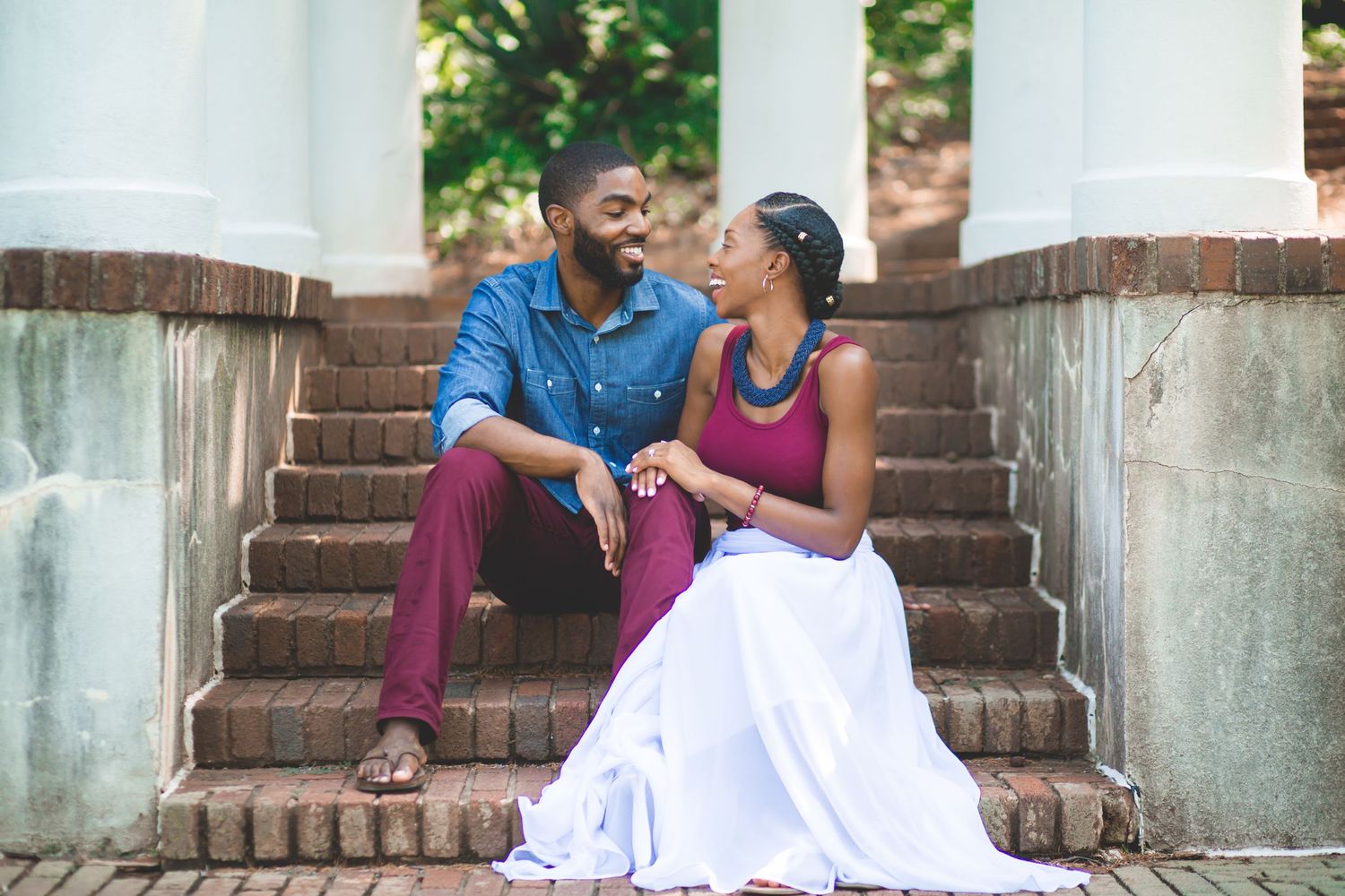 A couple shares an intimate moment while sitting on white stone steps outdoors.