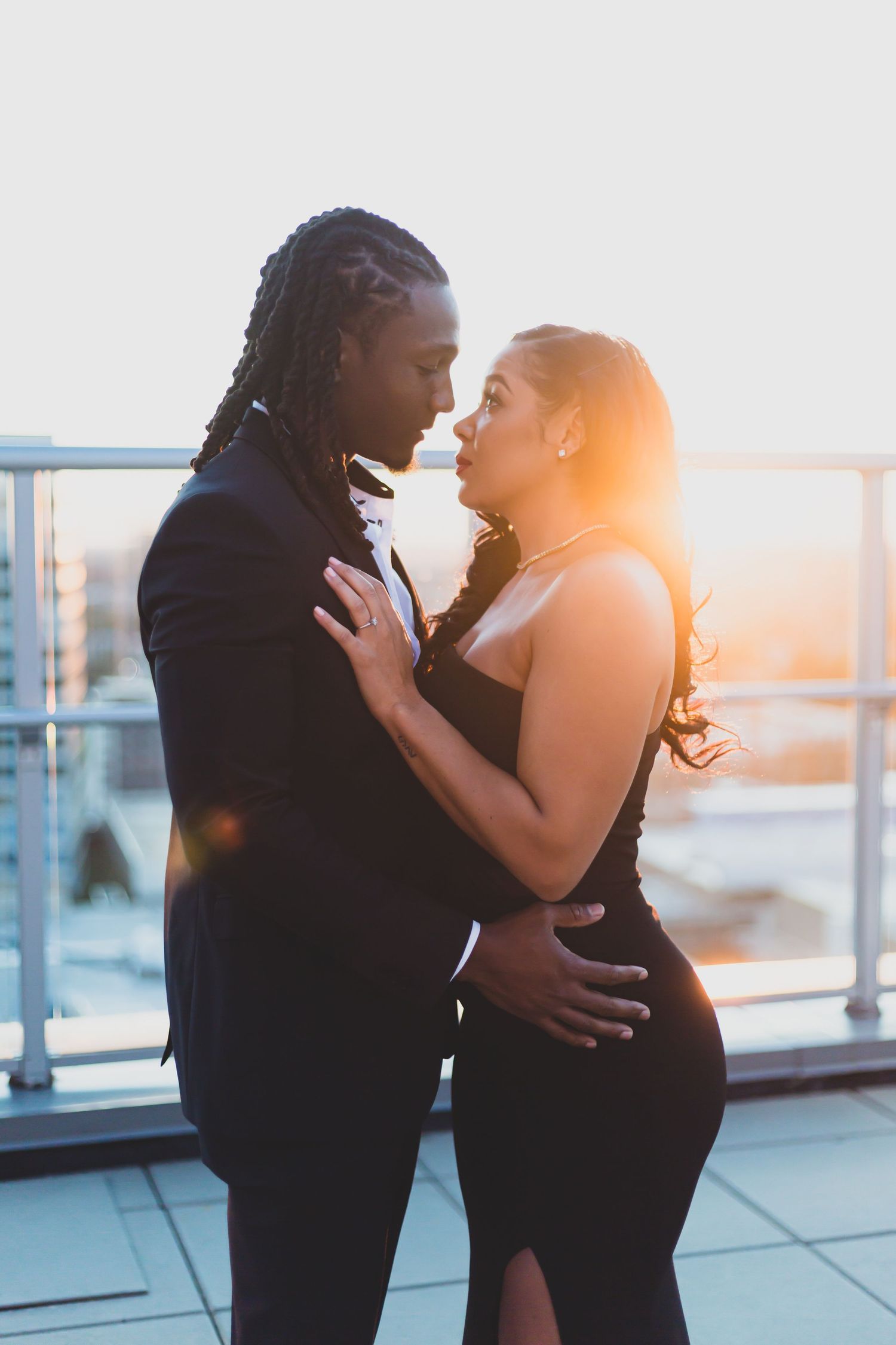 Romantic sunset silhouette of couple embracing on rooftop balcony.