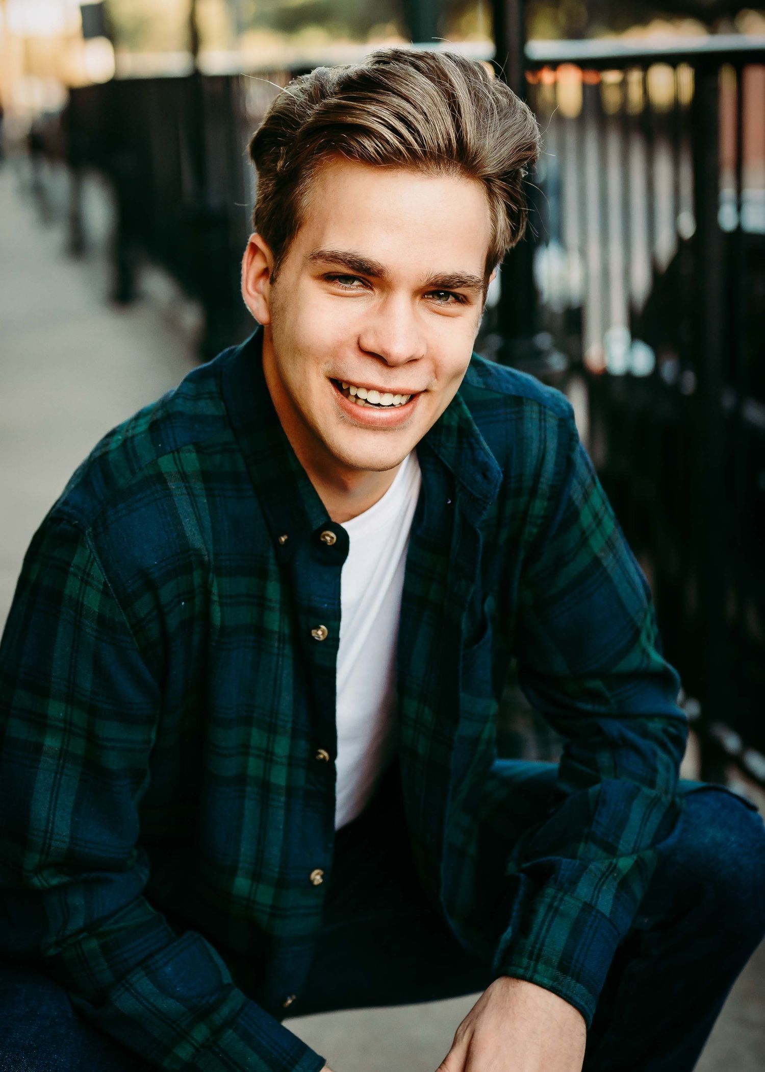 Casual outdoor portraits with plaid jacket against architectural backdrop.