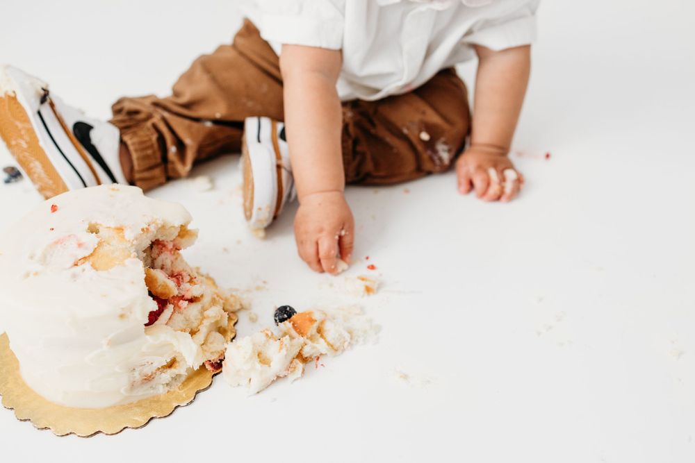 Details of smashed cake and little boy eating pieces from his cake smash in the studio. Los Alamos baby cake smash session.