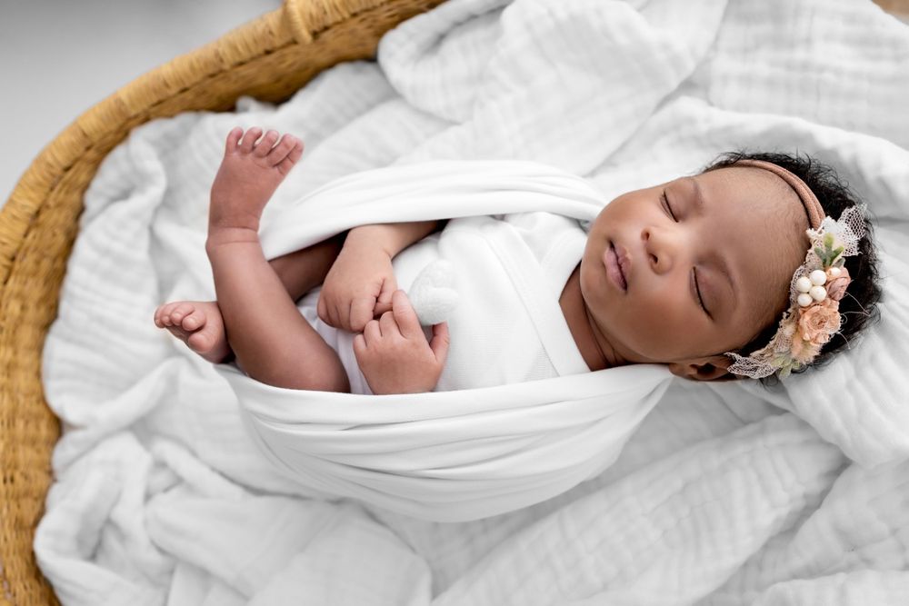 Newborn baby girl wrapped laying in a Moses basket in Santa Fe NM newborn photography studio
