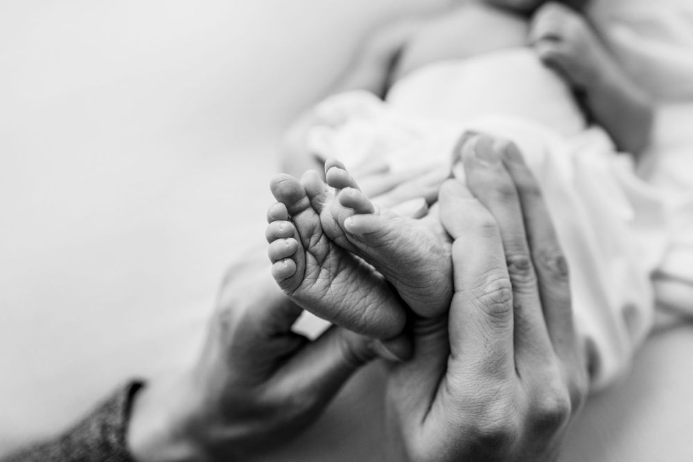 Black and white newborn detail mom holding newborn feet and toes in Blooming Desert Photography Studio in New Mexico. Los  Alamos Babies.