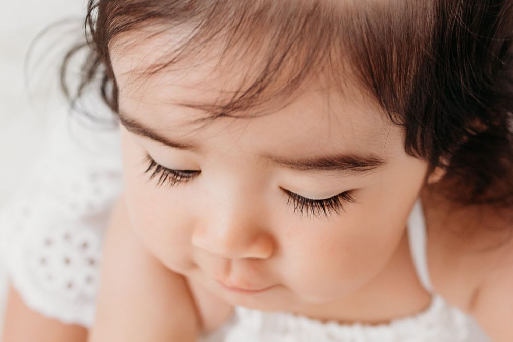 A series of close-up photos showing a baby's long dark eyelashes while playing