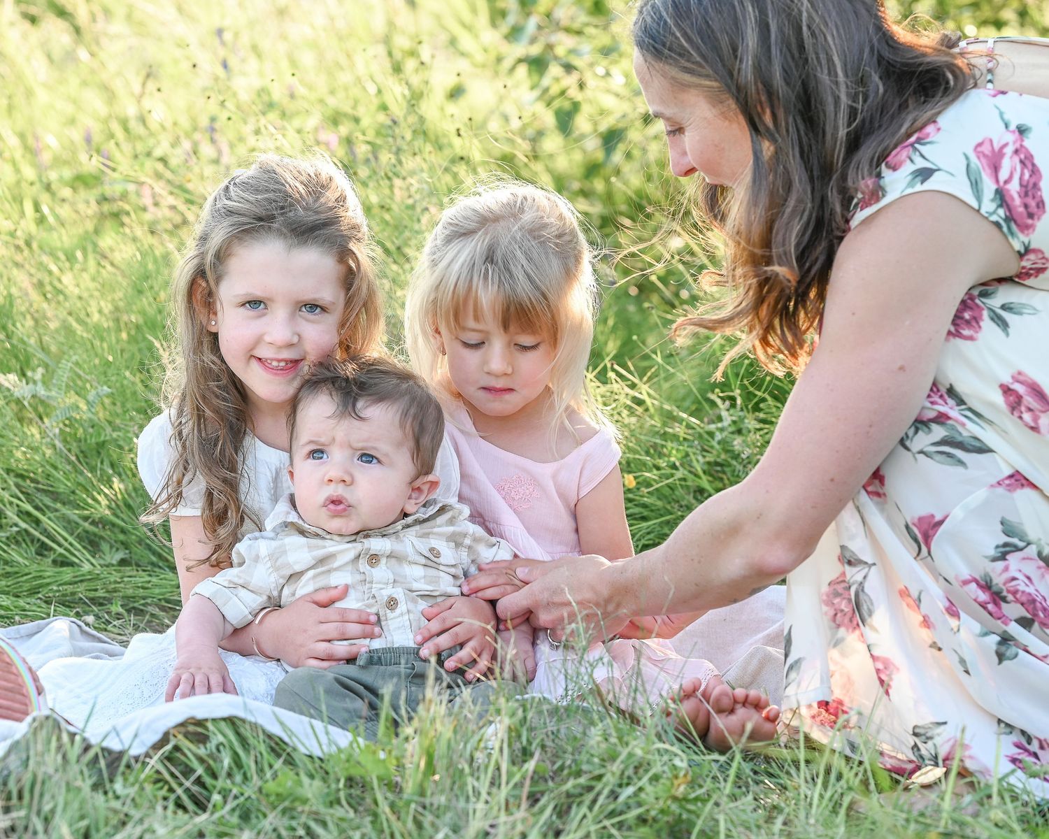 Two young sisters and baby brother with mom helping. Light and airy style.