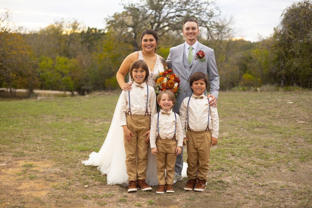 Wedding portrait in a natural outdoor setting with tan suspenders and rustic attire against an autumn backdrop.