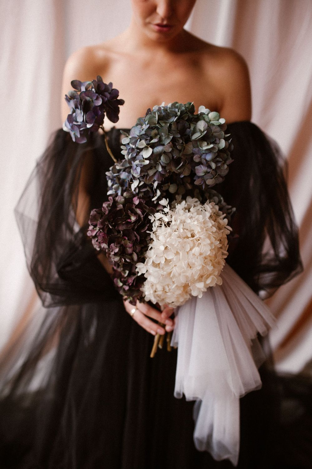 Artistic portrait showing a black tulle dress with white and purple hydrangea bouquet.