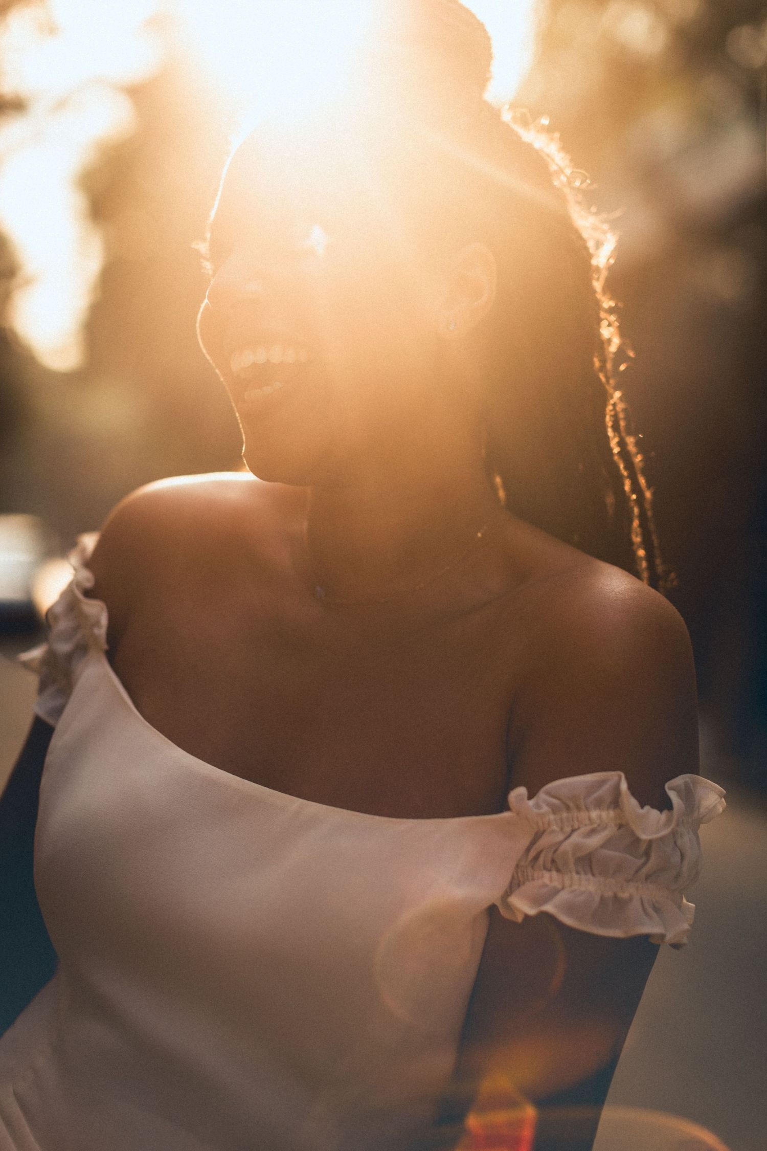 Ethereal backlit portrait of a bride in an off-shoulder wedding dress with sun flare.