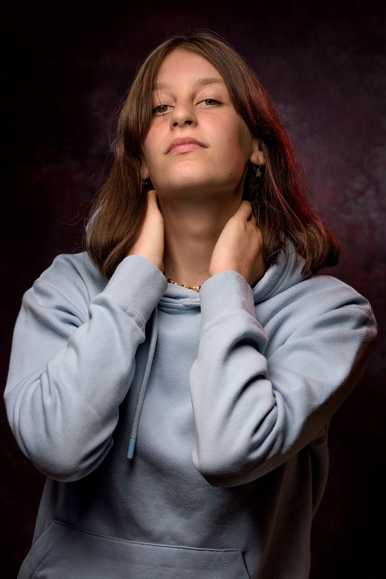 portret van een jongedame in de studio met haar handen in de hals