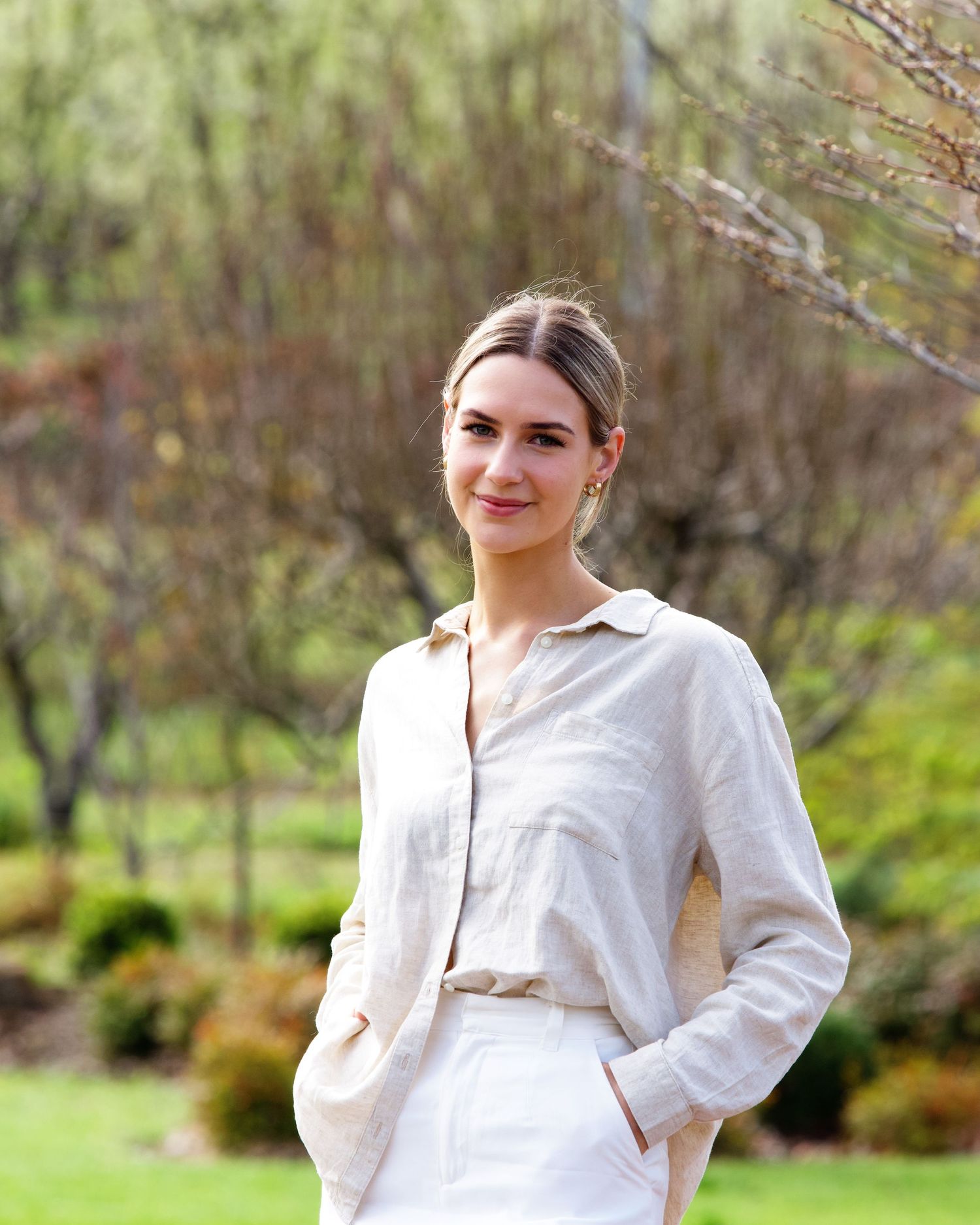 spring portrait of a female wearing cream shirt and white pants with hands in pocket