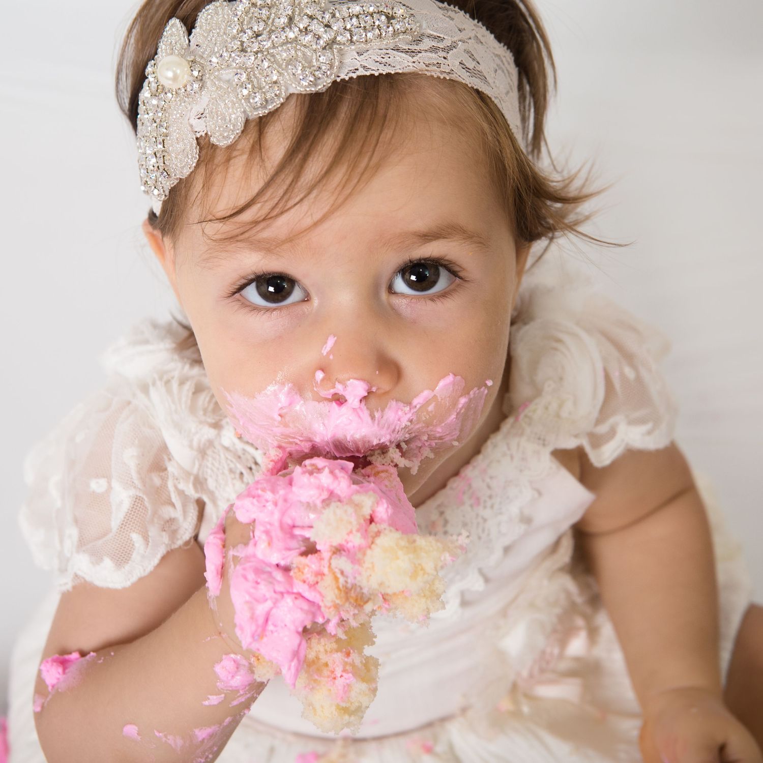 Cake Smash Photoshoot of little girl with cake all over her.