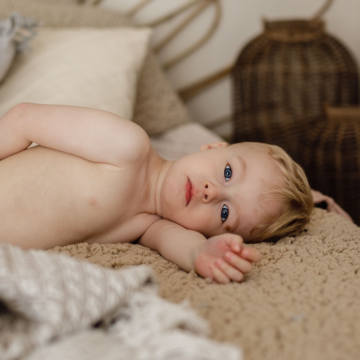 Baby Boy laying on the bed looking straight into the camera.