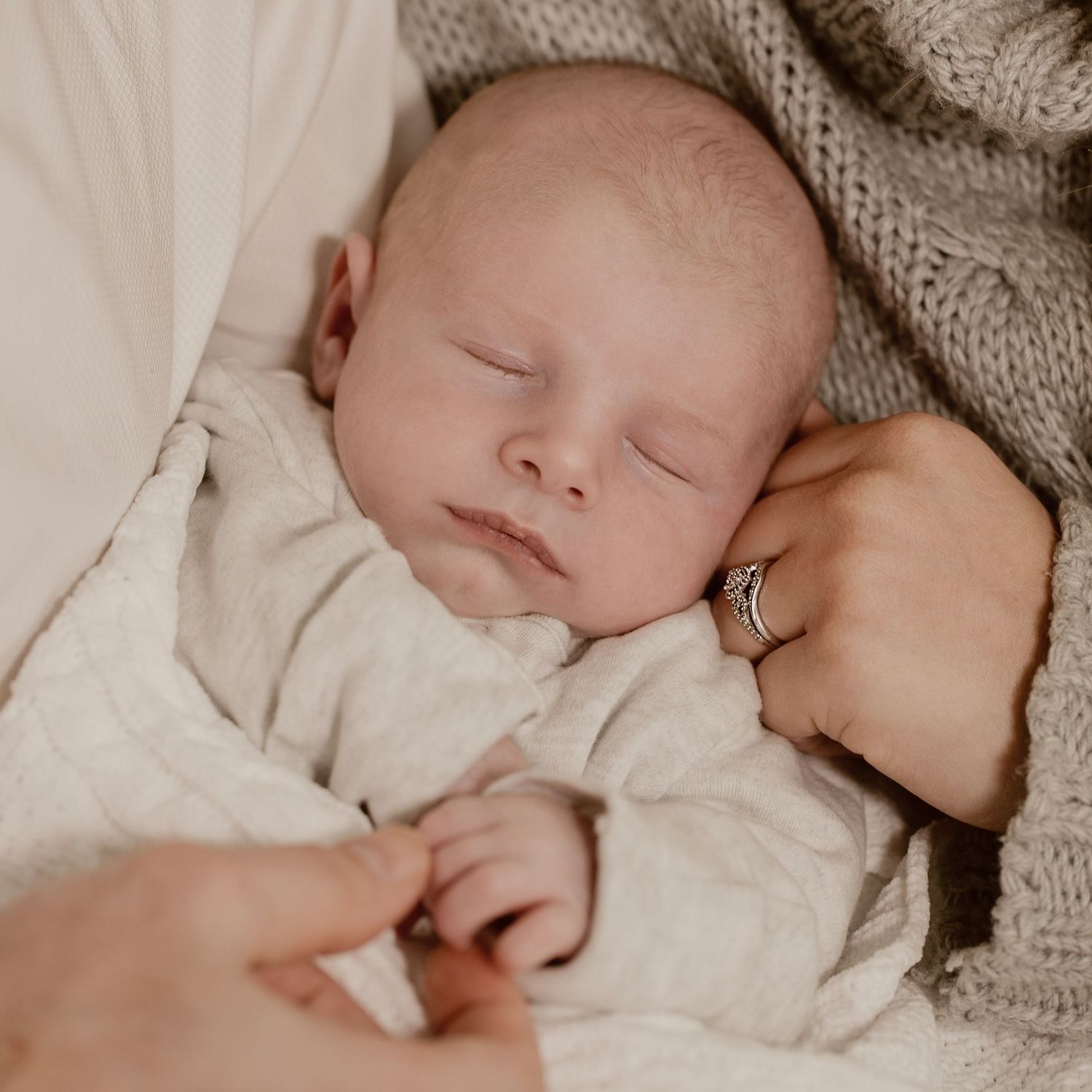 Family photography with close up shot of just newborn and mum and dads hands.
