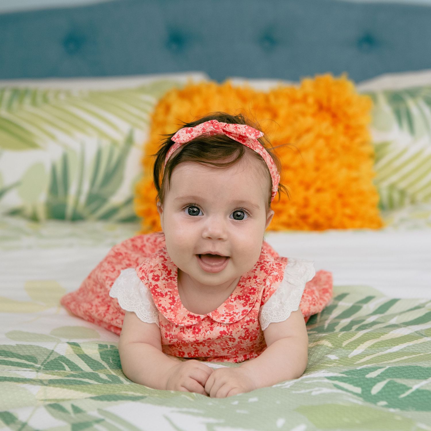 Baby Photography, 6 months old baby girl, laying on the bed on her tummy smiling.