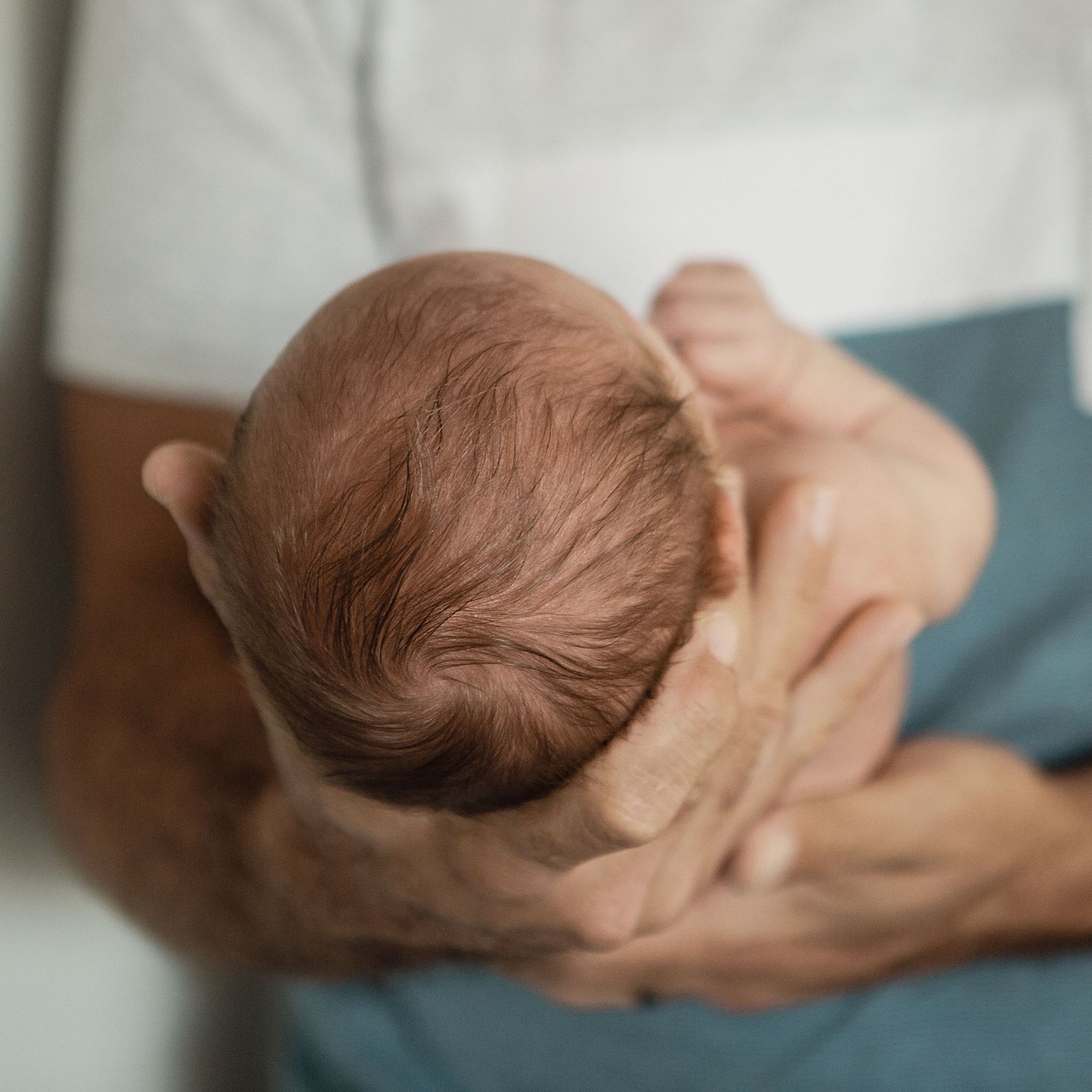 Newborn babys head. Dad holding him for his newborn photoshoot.