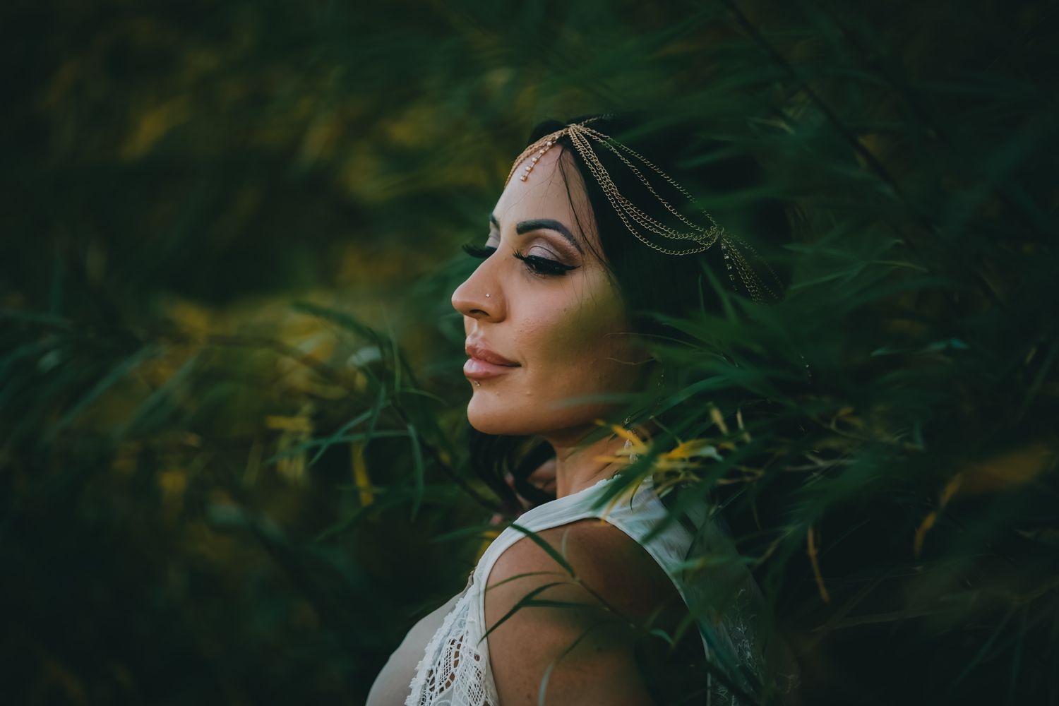 Side profile portrait of someone in nature with glowing golden light through foliage.