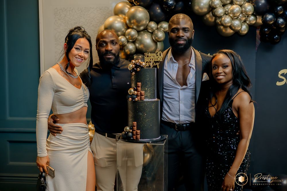 Group photo at an upscale event with gold and black balloon decorations.