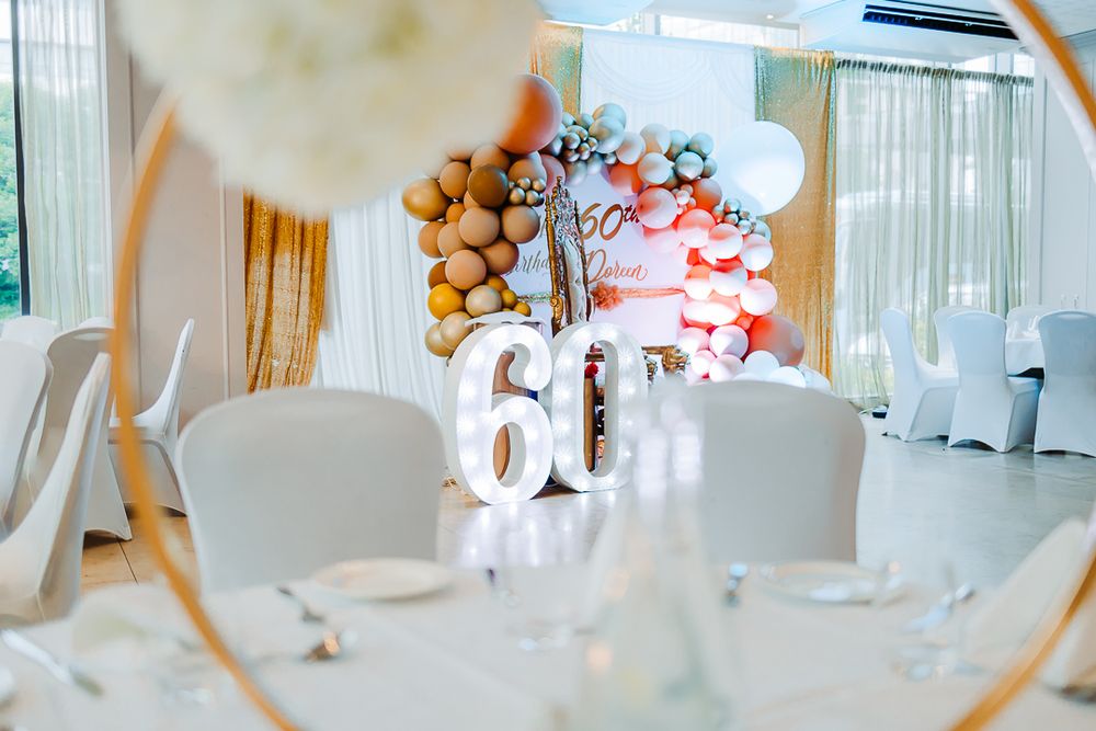 Elegant white party venue setup with balloon decorations and large 60th birthday numbers.