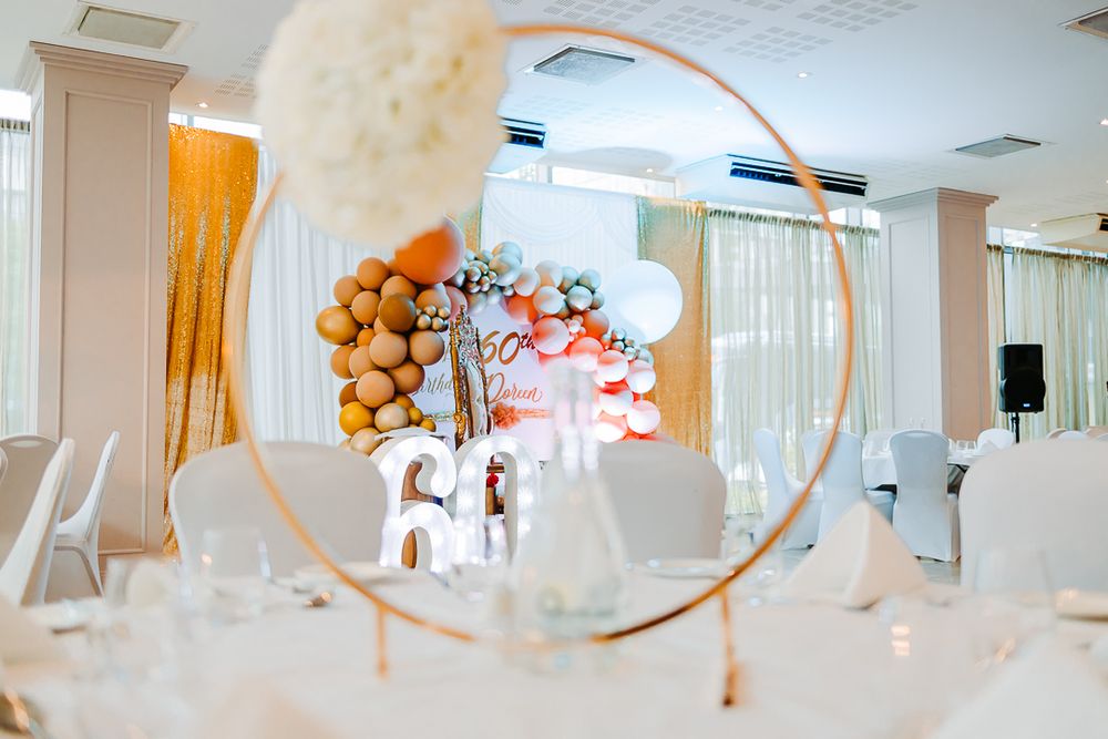 White party venue through circular frame with balloon arch and large 60 numbers.
