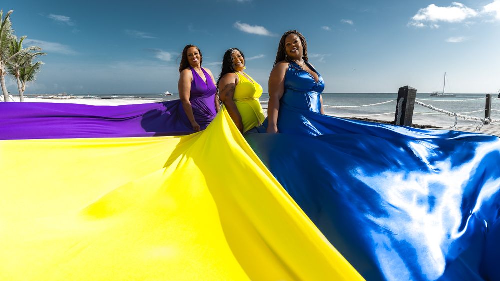 Flowing fabric in purple, yellow and blue colors against bright beach sky.