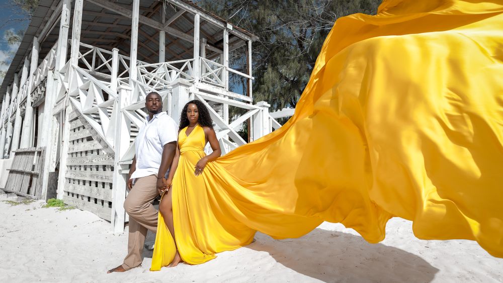 Yellow flowing dress fabric captured in motion against white coastal architecture.