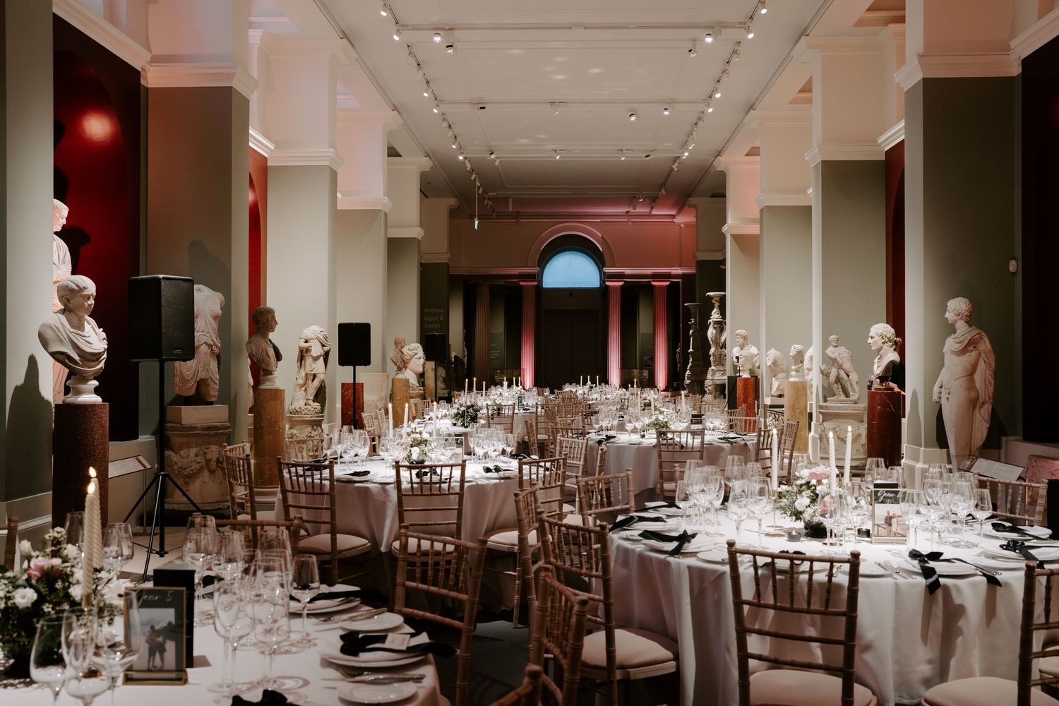 grand sculpture gallery dressed for the wedding breakfast with candles and flowers covering tables at the Ashmolean Museum in Oxford