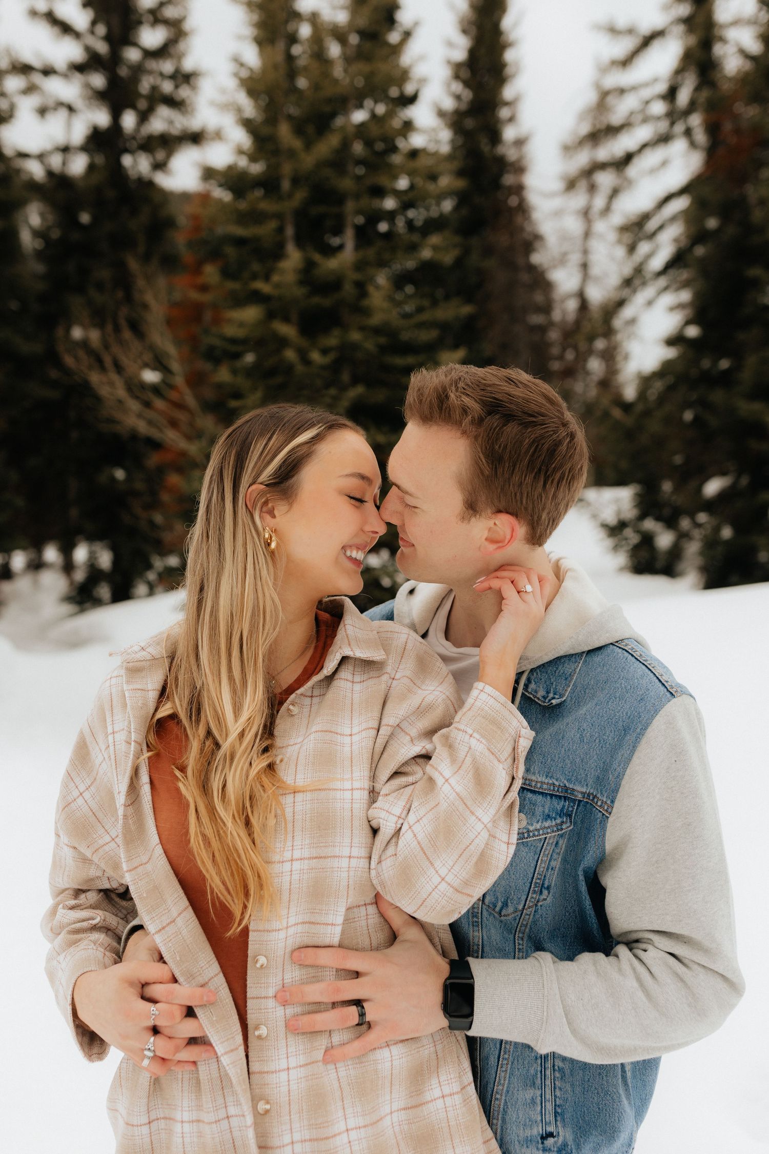 Man holding his fiancé from behind with her twisted around about to kiss him