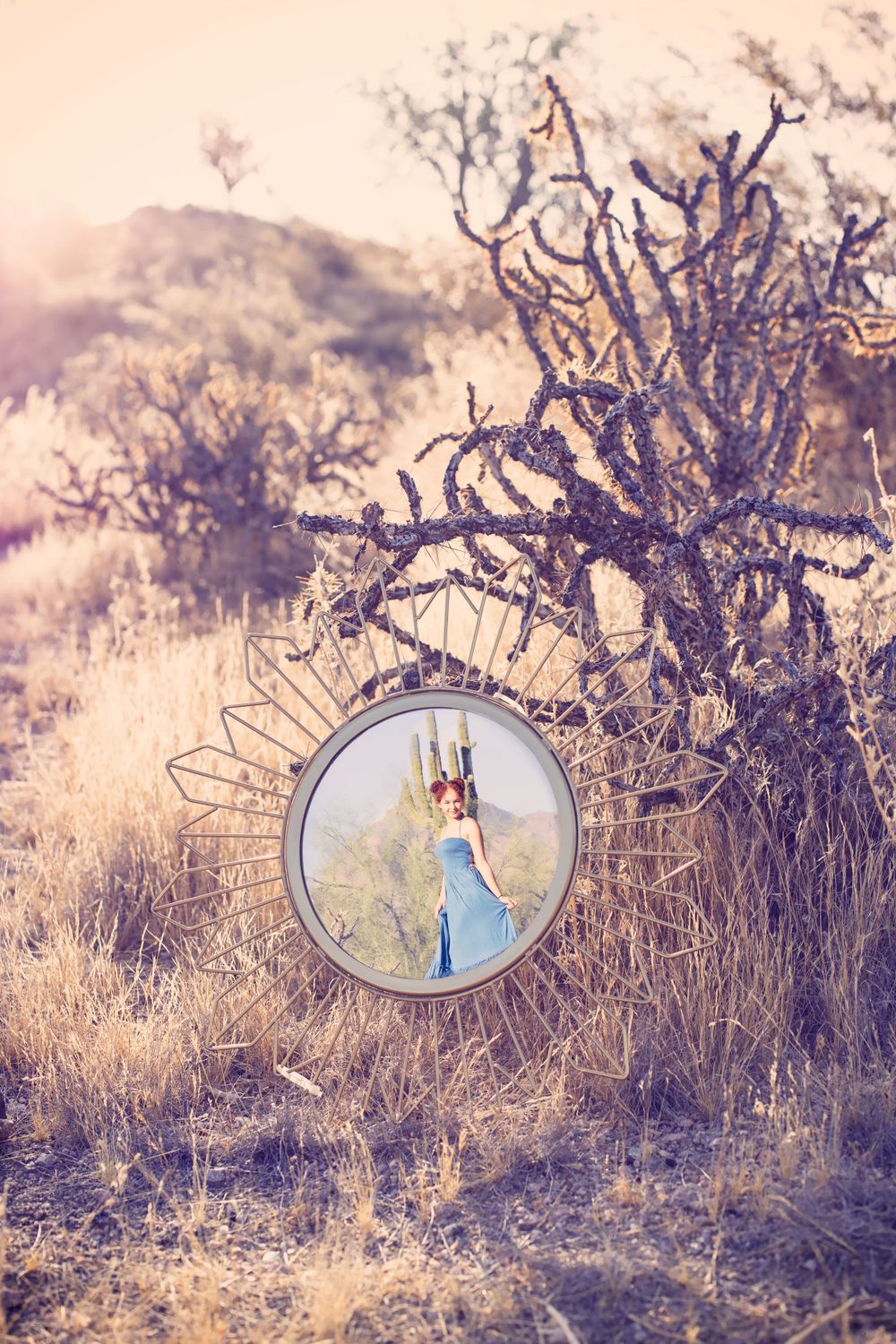 Artistic portrait through circular mirror frame in desert setting with cacti.