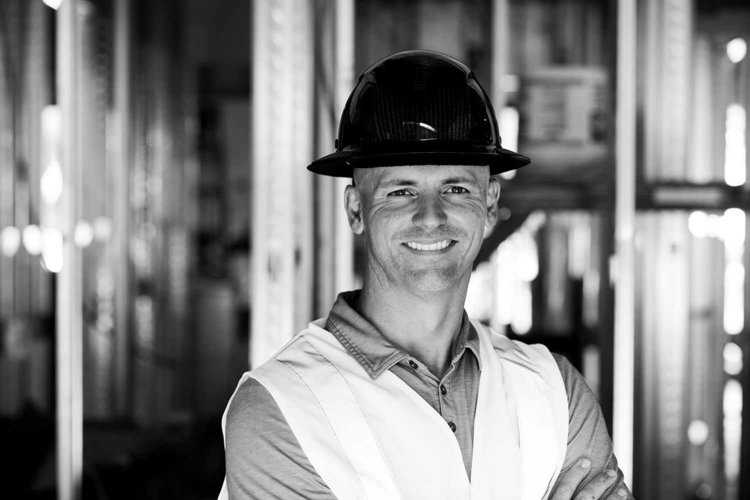 Black and white portrait of a construction worker wearing a hard hat and safety vest.