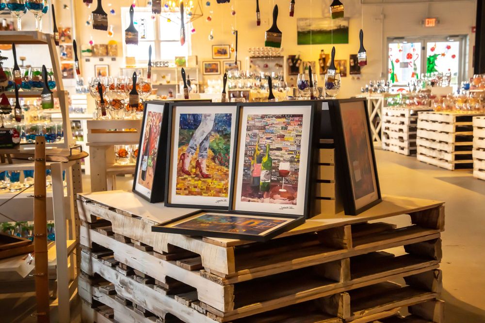 Retail shop interior with framed artwork displayed on wooden pallets.