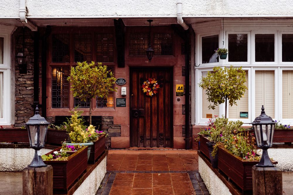 Charming entryway with wooden door, autumn wreath, and decorative planters.