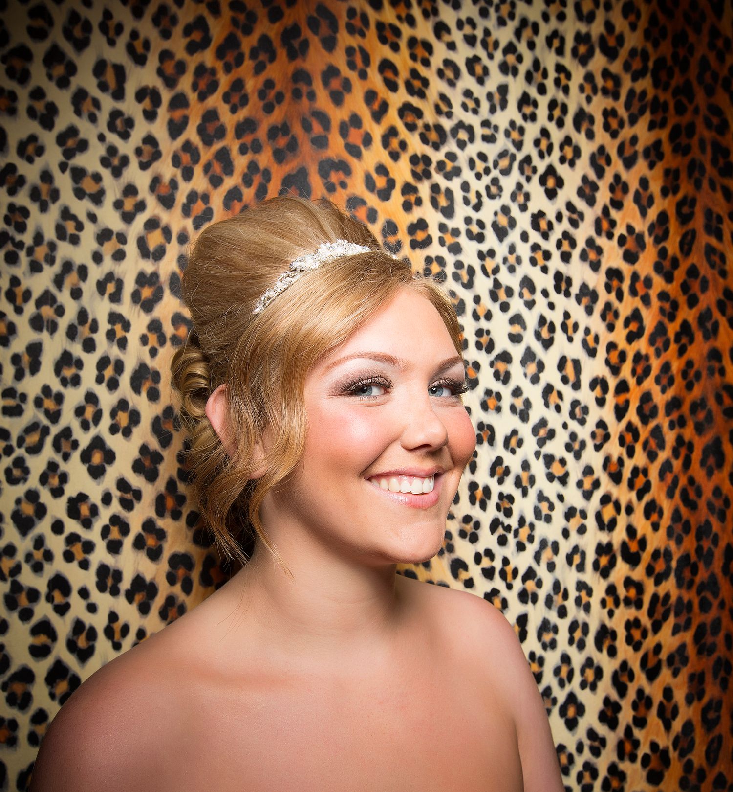 Portrait head shot of smiling blond haired bride against a leopard print wall