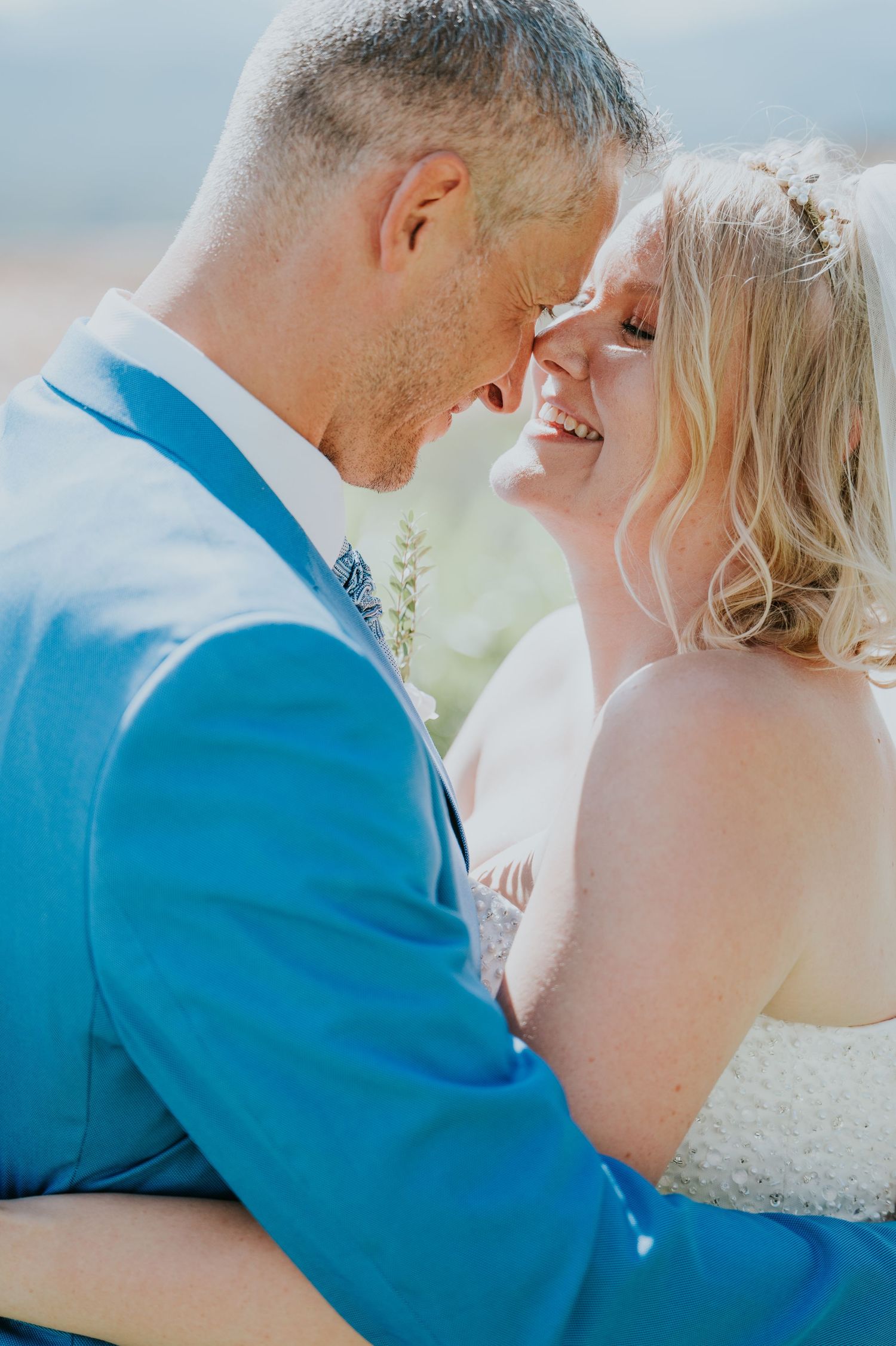 An intimate moment captured between newlyweds in bright natural sunlight.