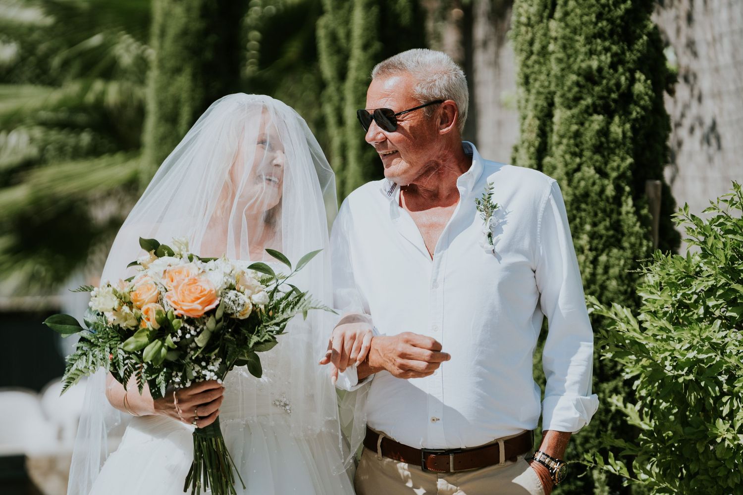 A couple shares a moment together among greenery at their outdoor wedding ceremony.
