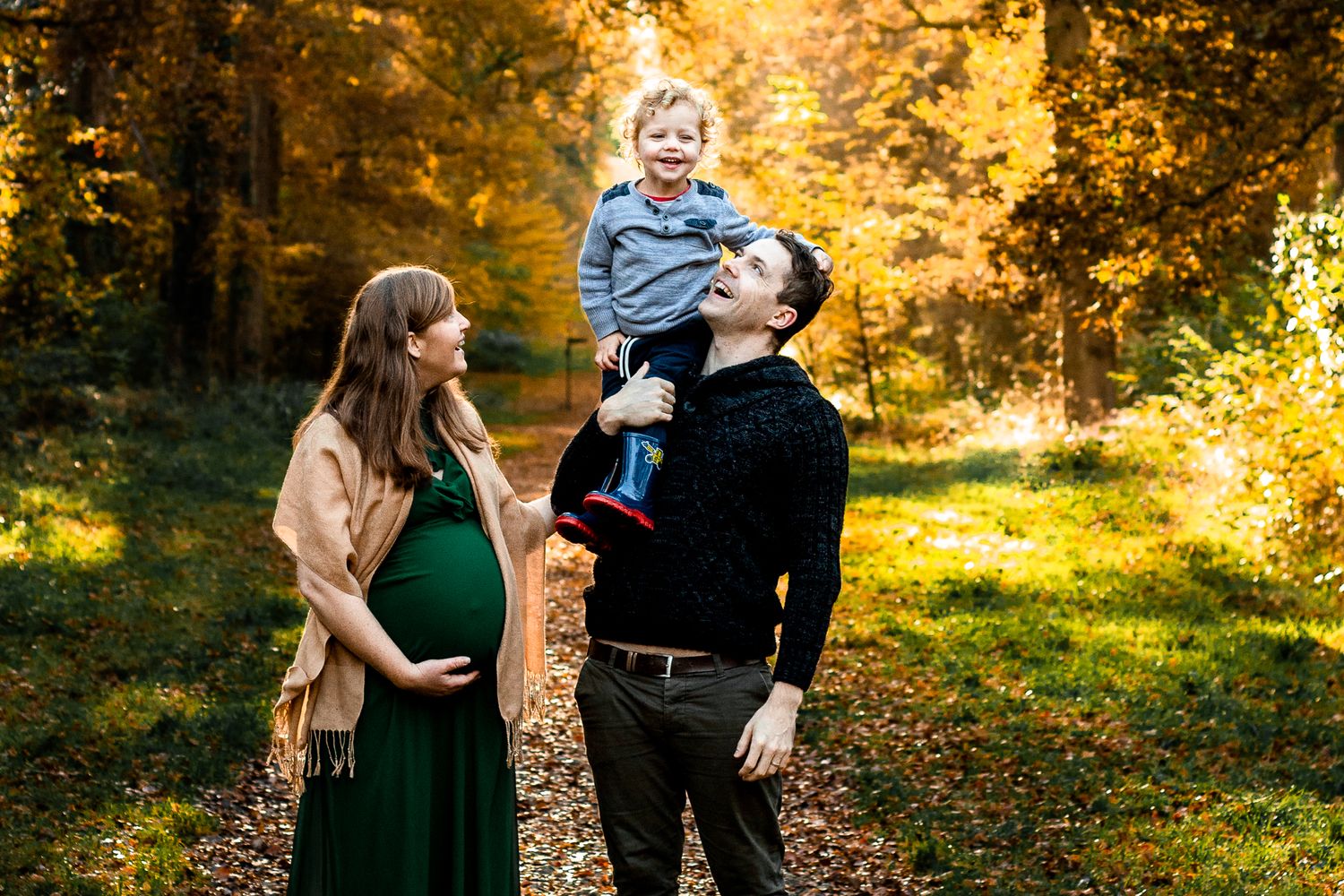 In the woods at Staunton country Park, Havant, a family a Mum and Dad laugh with their two year old Son.