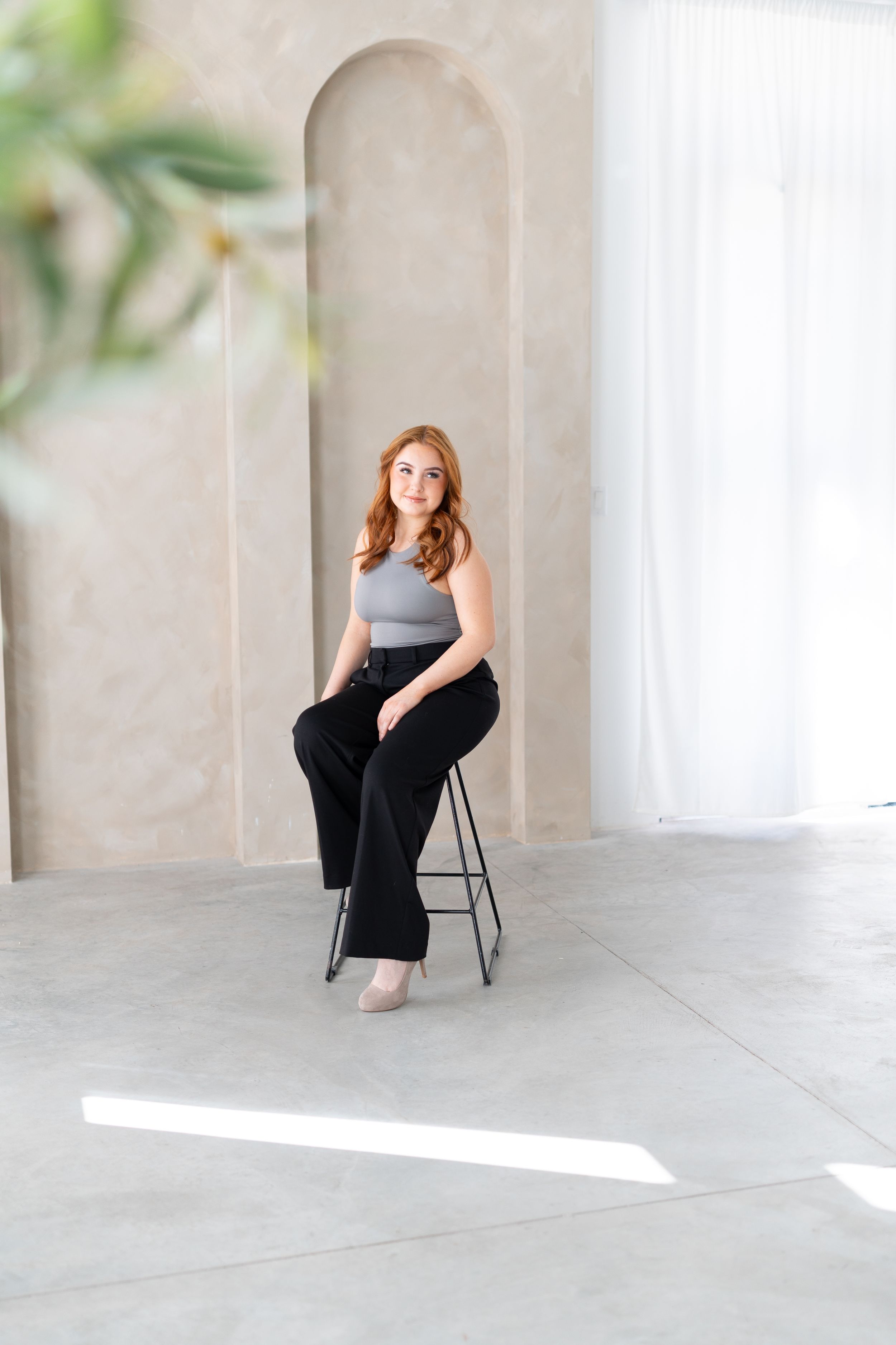 Professional indoor portrait with natural lighting through windows and an arched alcove setting.